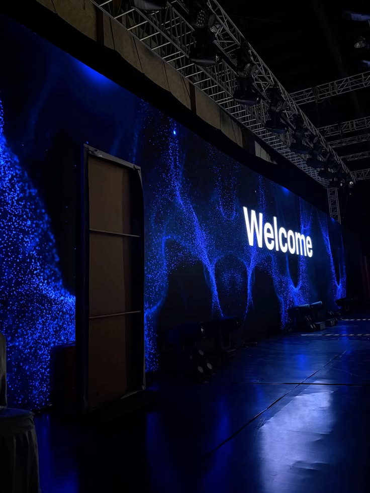 Blau beleuchtete LED-Wand mit Welcome-Schriftzug unter einer Traversenkonstruktion